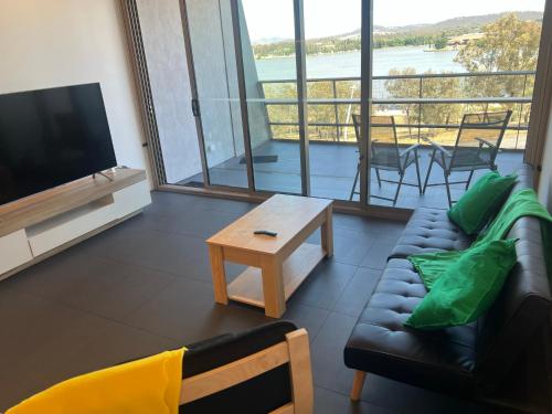a living room with a couch and a flat screen tv at Luxe 1 BR Retreat Lake Views at Nishi New Acton Canberra City in Canberra