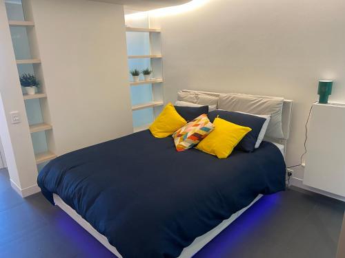 a bed with yellow and blue pillows in a room at Luxe 1 BR Retreat Lake Views at Nishi New Acton Canberra City in Canberra