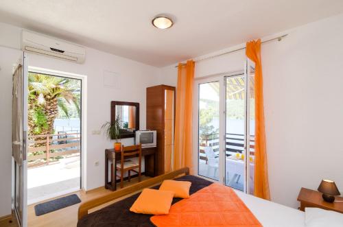 a bedroom with a bed with orange pillows and a balcony at Apartments Matana Chano in Polače