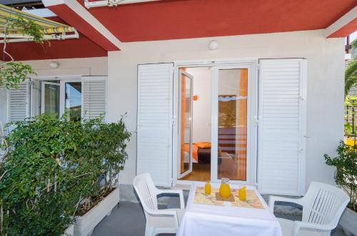 a patio with white chairs and a table with drinks on it at Apartments Matana Chano in Polače