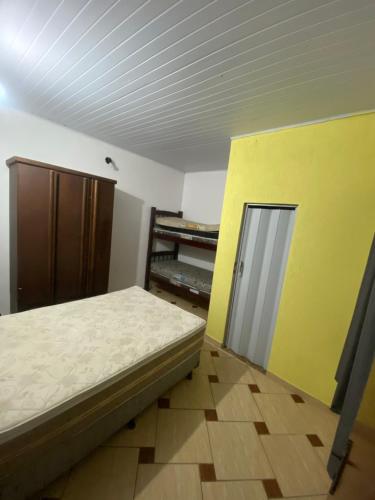 a bedroom with a bed and a yellow wall at Espaço Sol in Peruíbe