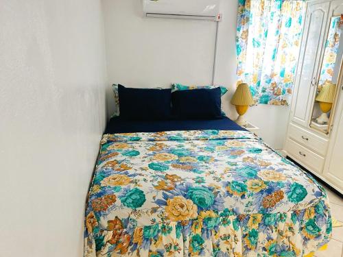 a bedroom with a bed with a floral quilt on it at Krystal Apartment in Grande Rivière