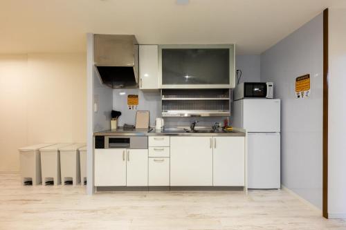 a kitchen with white cabinets and a white refrigerator at Tourist Hotel New Aoki 観光ホテル ニュー青木 in Tokyo