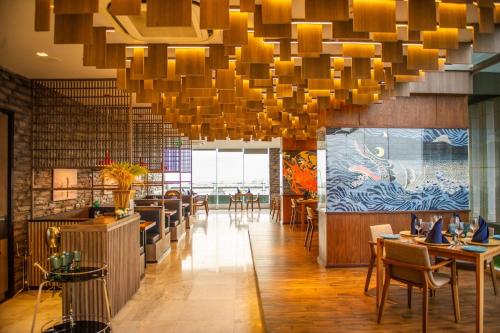 a restaurant with a large chandelier and tables and chairs at Oakwood Hotel & Residence Sri Racha in Si Racha