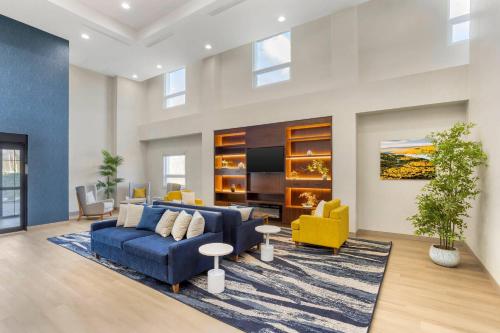 a living room with a blue couch and yellow chairs at Comfort Suites Central Valley - Woodbury in Central Valley