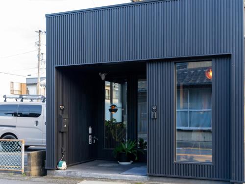 a black building with a door open in front of a van at Rino-Haku 03 in Anan