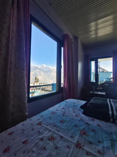 a bedroom with a bed and a large window at Bilju Homestay in Munsyari