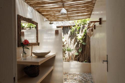 een badkamer met een wastafel en een spiegel bij Casa do Amor Caraíva in Caraíva