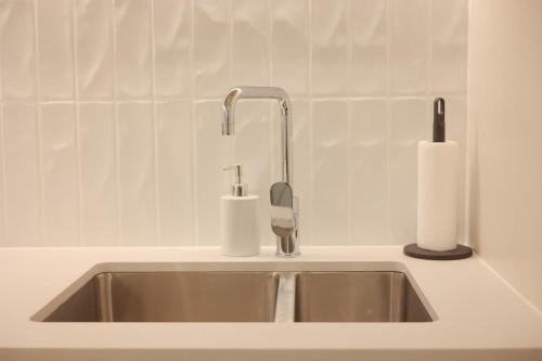 a kitchen sink with a faucet and a roll of paper towels at VTA - Modern 1BR Apt in the Heart of Adelaide in Adelaide