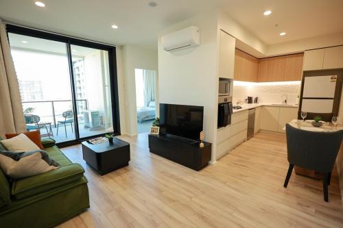a large living room with a couch and a kitchen at VTA - Modern 1BR Apt in the Heart of Adelaide in Adelaide