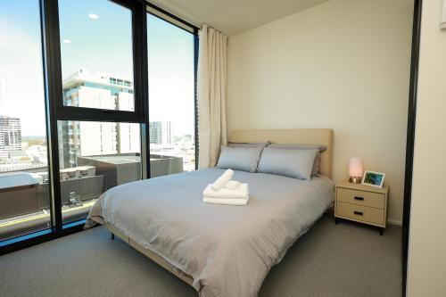 a bedroom with a bed with two towels on it at VTA - Modern 1BR Apt in the Heart of Adelaide in Adelaide