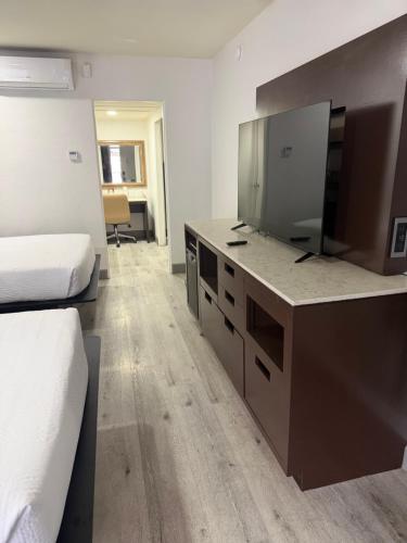 a room with two beds and a dresser with a mirror at DTLV, a Baymont by Wyndham in Las Vegas