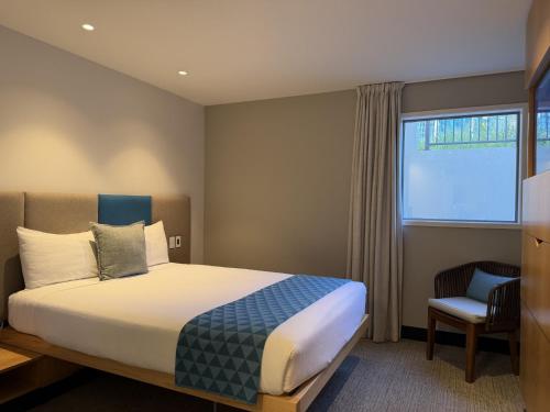 a bedroom with a bed and a chair and a window at mi-pad Queenstown in Queenstown