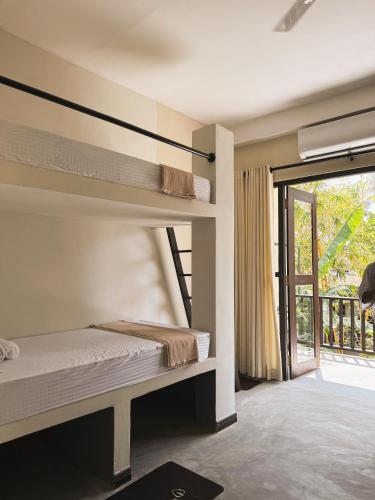 a bedroom with a bunk bed and a large window at Nirvana Surf Retreat - Kabalana in Atadahewatugoda