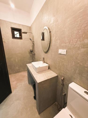 a bathroom with a sink and a mirror and a toilet at Nirvana Surf Retreat - Kabalana in Atadahewatugoda