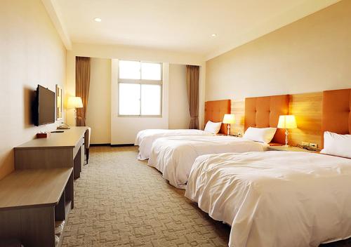 a hotel room with three beds and a flat screen tv at Jade Garden Hotel - 翠華會館 in Gukeng