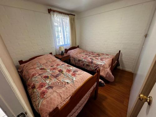 a bedroom with two beds and a window at Los Castaños Pucón in El Cerrillo