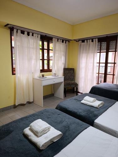 a bedroom with two beds and a desk and windows at Piso entero La Boca in Buenos Aires