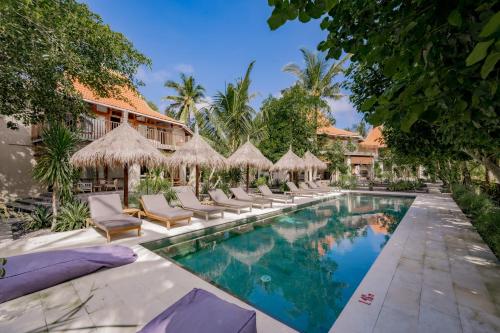 an image of a resort pool with chairs and umbrellas at Amrani Diamond Beach Villas & Pool in Nusa Penida