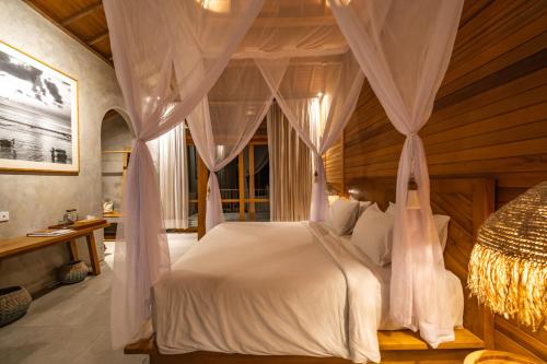 a bedroom with a canopy bed with curtains at Amrani Diamond Beach Villas & Pool in Nusa Penida