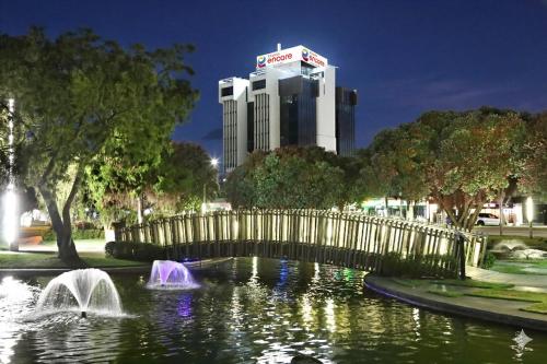 a bridge over a pond with a building in the background at Ramada Encore by Wyndham Palmerston North in Palmerston North