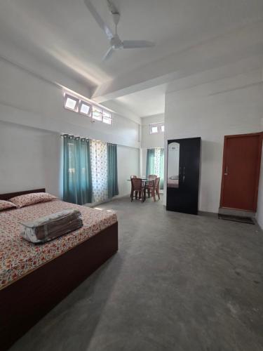a bedroom with two beds and a table and chairs at The White House By Bhaskar Homestay in Dibrugarh