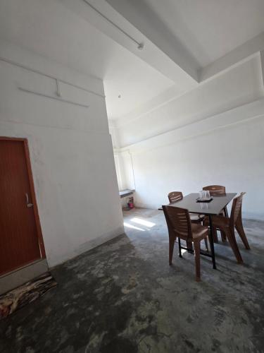 a dining room with a table and chairs in an empty room at The White House By Bhaskar Homestay in Dibrugarh