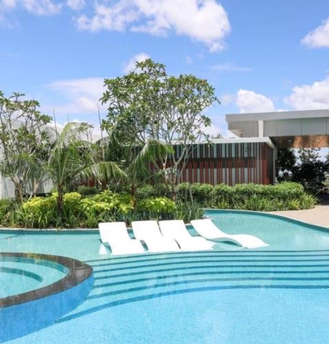 a swimming pool with white lounge chairs next to a building at Aisy Suite Splash Mania View in Bandar Gamuda Cove