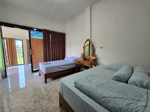 a bedroom with two beds and a mirror at Keramas Selukat Guest House in Keramas