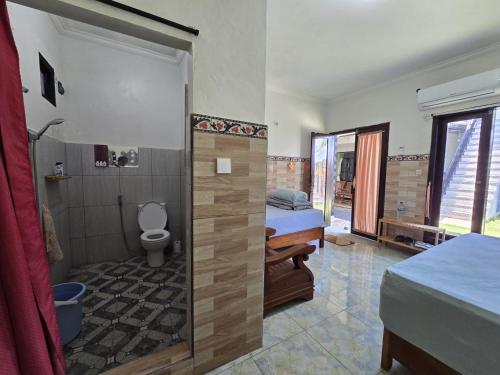 a bedroom with a bathroom with a shower and a toilet at Keramas Selukat Guest House in Keramas