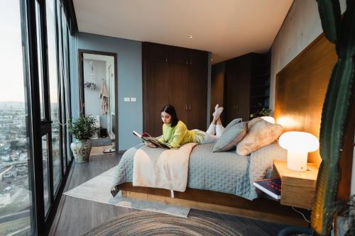 a woman sitting on a bed reading a book at Volcano View Loft, Puebla Skyline1801 in Puebla