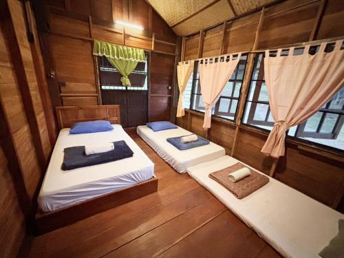 twee bedden in een kamer met houten wanden en ramen bij Baandindon Private Earthhouse Homestay in Mae Rim