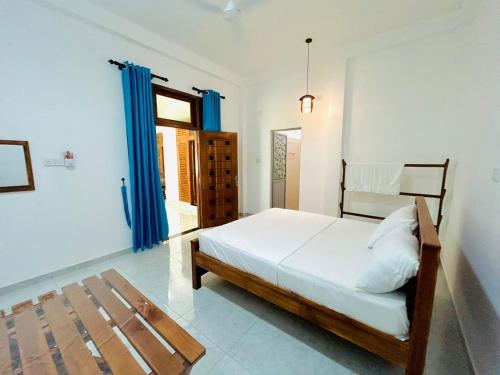 a bedroom with a large bed and blue curtains at Blue Heaven Guest House Wellawaya in Wellawaya