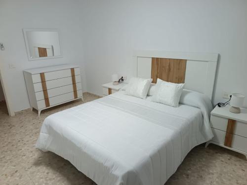 a white bedroom with a large white bed and two tables at Antonio del Toro in Lora del Río