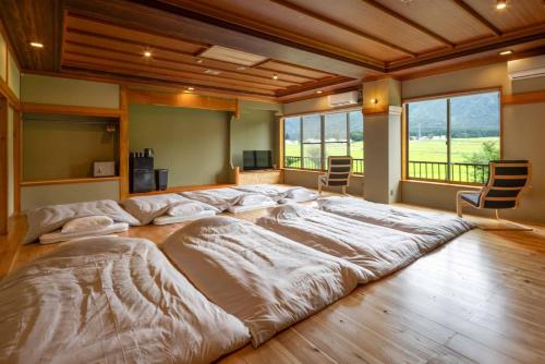 a large bed in a room with chairs and windows at IkazawaYumotokan in Minami Uonuma