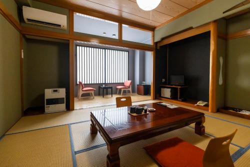 a living room with a wooden table and chairs at IkazawaYumotokan in Minami Uonuma