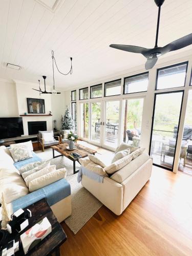 a living room with two couches and a ceiling fan at Sydney Northern Beaches Pitterwater Waterfront Holiday House Avalon Beach - Clareville in Clareville