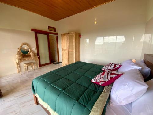 a bedroom with a green blanket on a bed at Rumah Bagus Jayanti in Sidemen