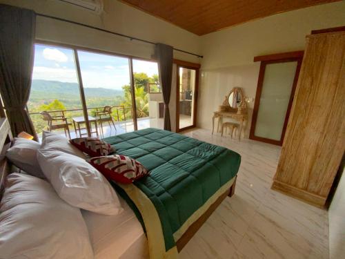 a bedroom with a large bed and a balcony at Rumah Bagus Jayanti in Sidemen
