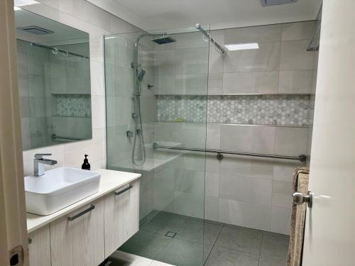a white bathroom with a sink and a shower at Coolamon in Ballina