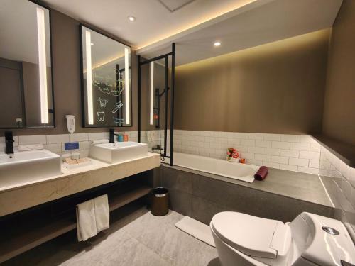 a bathroom with two sinks and a toilet and a tub at Citadines Connect Airport Jakarta Hotel in Tangerang