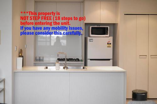 a kitchen with a sink and a refrigerator at Cozy 2-bedroom Apartment, Free Parking, close to Olympic park in Sydney