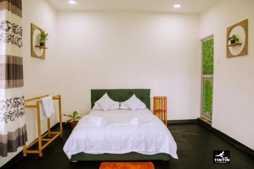 a bedroom with a bed with white sheets and pillows at Tin Tin Lodge in Ella