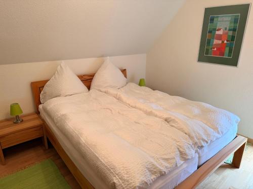 un letto con lenzuola e cuscini bianchi in una stanza di Kuckucksnest a Ühlingen-Birkendorf