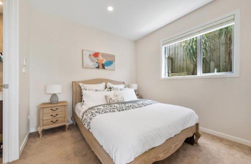 a white bedroom with a bed and a window at Blue Horizon in Auckland
