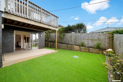 a backyard with a wooden fence and green grass at Blue Horizon in Auckland
