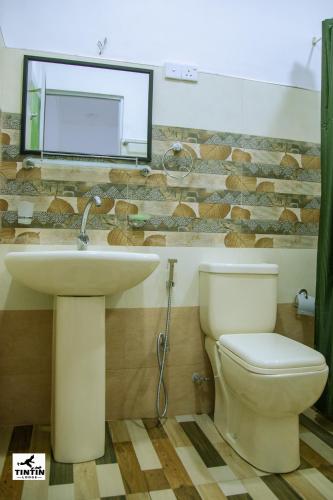a bathroom with a sink and a toilet and a mirror at Tin Tin Lodge in Ella