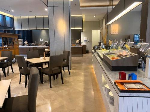 a restaurant with tables and chairs and a kitchen at Citadines Connect Airport Jakarta Hotel in Tangerang