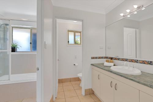 a white bathroom with a sink and a shower at Barefoot Haven in Amity Point