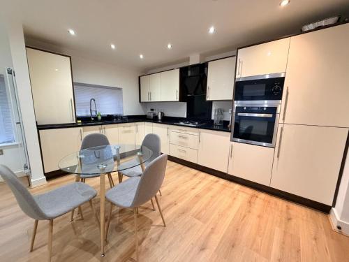 a kitchen with a glass table and chairs at Sleek Modern 2BDR Flat in Charming Pinner in Northwood